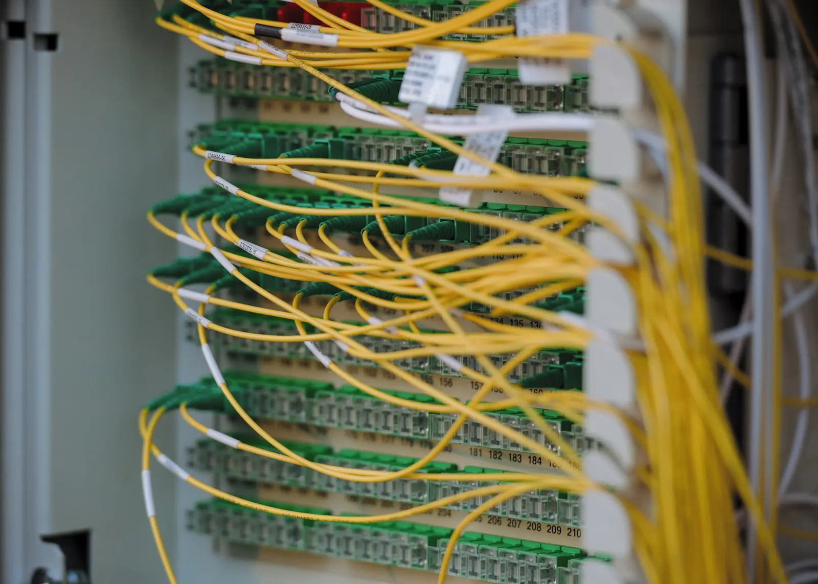 Yellow fibre-optic cables patched into a network panel.